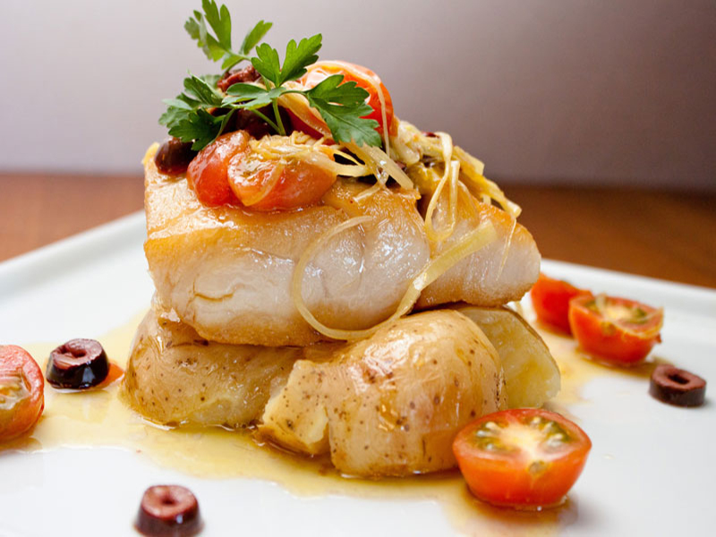 baked fish on roasted potatoes with cherry tomatoes